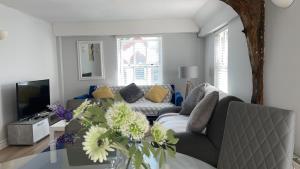 ein Wohnzimmer mit einem Sofa und einem Tisch mit Blumen in der Unterkunft Colchester Town Duplex Apartment in Colchester