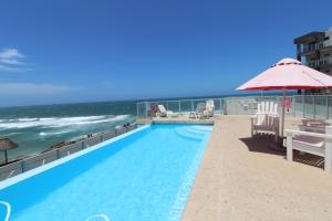 ein Pool mit Sonnenschirm und das Meer in der Unterkunft Seagull 314 in Margate