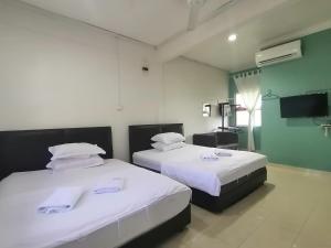 龙运FBS Inn Dungun的一间卧室，配有两张铺有白色床单的床
