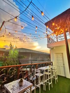 un patio con mesas blancas, sillas y luces en NomadsMNL Hostel, en Manila