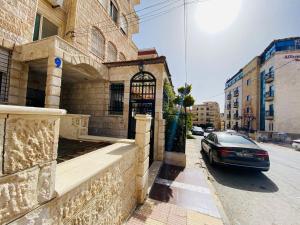 um carro estacionado em frente a um edifício numa rua em شقه مفروشة الجبيهه em Amã