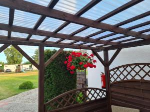 a wooden pergola with a hanging basket of red flowers at Ośrodek Wypoczynkowy Ostoja in Dźwirzyno