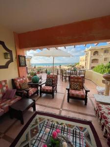 a patio with chairs and tables and an umbrella at EL Fouly Villa with beach front فيلا لمة العيله الفولي - سيدي كرير in Abû Zeira