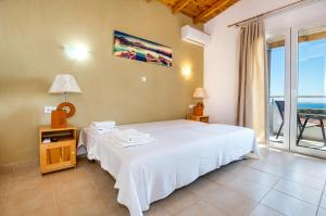 una camera da letto con un letto bianco e una grande finestra di Studios Evrika a Skala Marion