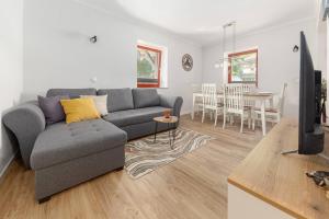 Sala de estar con sofá gris y mesa en Apartments Ribnica, en Bohinj