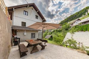 un patio con mesa y sombrilla en Apartments Ribnica, en Bohinj