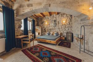 a bedroom with a bed and a stone wall at Pinhan Cave Suites in Uçhisar