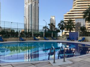 a large swimming pool with blue chairs and buildings at Frank Porter - Marina Terrace in Dubai