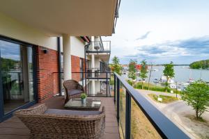a balcony with chairs and a table and a view of the water at Lake Rental Spacerowa in Mikołajki