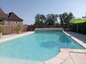 una piscina con sombrilla en un patio en Gîtes Périgord Rocamadour Sarlat Gourdon naturiste de juin à sept, en Salviac