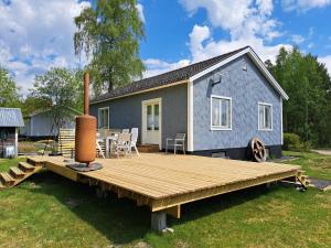 a blue tiny house with a wooden deck at Vakantiehuis SARAH- vlakbij meer- van S&G Holiday in Nykroppa
