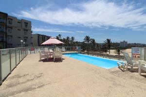 einem Pool mit Stühlen und einem Sonnenschirm neben einem Gebäude in der Unterkunft Seagull 409 in Margate