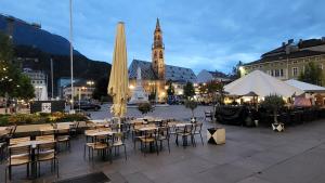 um grupo de mesas e cadeiras em frente a um edifício em Dolomiti 2 rooms Apartment Center WiFi TVsmart AC em Bolzano