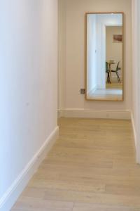 pasillo con espejo y suelo de madera en Gorgeous New 2 Bed Flat - 2 August House, en Londres
