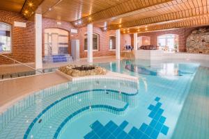 a large swimming pool with blue water in a building at Nordsee Hotel Borkum in Borkum