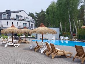 um grupo de cadeiras e guarda-sóis ao lado de uma piscina em Apartament Bursztyn em Pobierowo