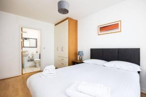 a bedroom with a white bed and a bathroom at Lovely 2 BR apartment with balcony in Dublin