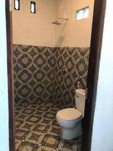 a bathroom with a toilet and a tiled wall at Tetebatu Fullmoon in Tetebatu