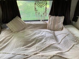 a bed with white sheets and pillows and a window at Karavan Na Louce in Volenice