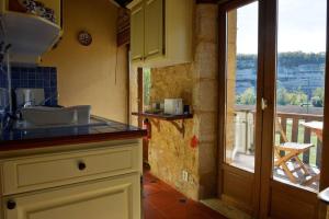 eine Küche mit einer Theke und Blick auf einen Balkon in der Unterkunft Cosy gîte with magnificent view, private terrace and shared swimming pool in Peyzac-le-Moustier