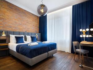 a bedroom with a bed with blue sheets and a brick wall at Tyzenhauz Grand Apartaments in Kraków