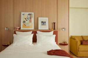 a bedroom with a bed with white pillows and a yellow chair at OKKO Hotels Paris Rosa Parks in Paris