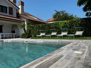 a swimming pool with chairs next to a house at VILLA SALICE 9.2 in Isola Albarella