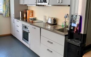 cocina con armarios blancos y nevera negra en Sitla Hotel & Appartments en Øvre Årdal