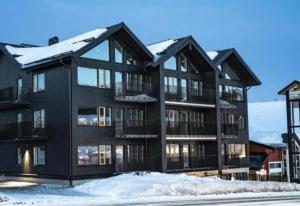 ein schwarzes Apartmenthaus mit Schnee auf dem Boden in der Unterkunft Fjällglim 22 Sälfjällstorget in Sälen