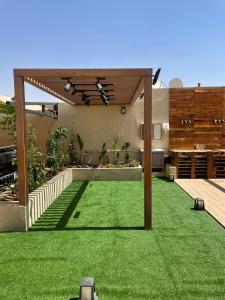 a backyard with a green lawn and a pergola at إستراحة الدنيس الونيس in Riyadh