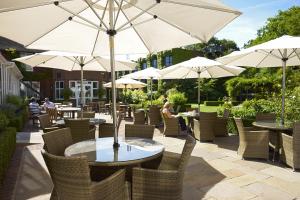 un patio con mesas, sillas y sombrillas en The Bull, en Gerrards Cross