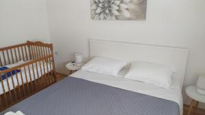 1 dormitorio con cuna y 1 cama con sábanas blancas en Apartman Greta Sukošan, en Sukošan