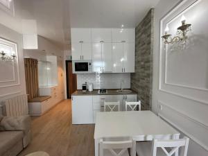 a kitchen with white cabinets and a white table at Moonlight Apart-Hotel Batumi in Batumi