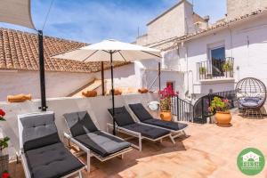 a group of chairs and an umbrella on a patio at Town house with jacuzzi and foosball table in Viñuela