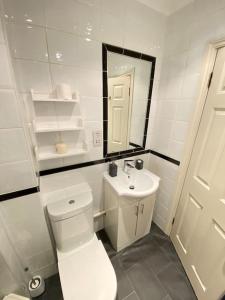 Baño blanco con aseo y lavamanos en Wonderful Baker Street Flat!, en Londres