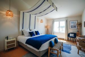 um quarto com uma cama com lençóis azuis e uma janela em Hôtel Le Noirmoutier em Barbâtre