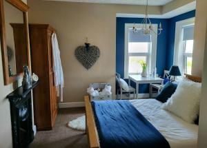 a bedroom with blue walls and a bed and a desk at Ocean Retreat Norfolk in Trimingham