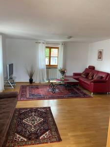 sala de estar con sofá rojo y alfombra en Nabo Ferienwohnung Lechbruck, en Lechbruck