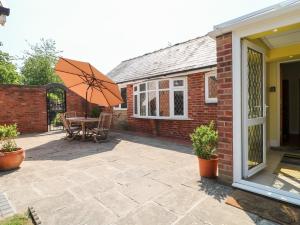 a patio with a table and an umbrella at Elm Tree Cottage in Melton Mowbray