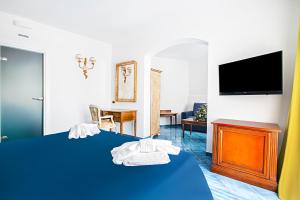 a hotel room with a blue bed and a tv at Hotel Villa Pandora in Maiori