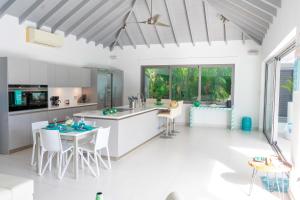 a kitchen with white cabinets and a table and chairs at VIP The Beach House in Jolly Harbour