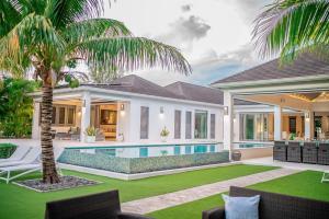 a house with a swimming pool and a palm tree at VIP The Beach House in Jolly Harbour
