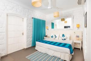 The Tamarind Hotel Goa في أنجونا: غرفة نوم بسرير وستارة زرقاء
