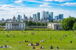 Menschen, die auf einem Feld vor einem Gebäude mit einer Stadt sitzen in der Unterkunft Massive Flat Near Greenwich Park( with office) in London