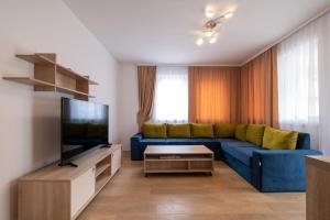 a living room with a blue couch and a tv at Countryside Resort Sarajevo in Hadžići