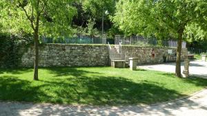 a park with a bench and a stone wall at Camping Alpino - Nature Village in Malcesine