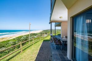 einen Balkon mit Tisch und Stühlen sowie Strand in der Unterkunft Sancta South Coast 2 bedroom Apartment in Kingsborough