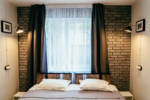 1 dormitorio con 1 cama y una ventana con cortinas en Villa Fortuna, en Ludza