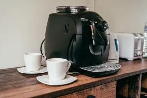 eine Kaffeemaschine auf einer Holztheke mit zwei Tassen in der Unterkunft Villa Fortuna in Ludza