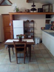 eine Küche mit einem Tisch und Stühlen sowie einem Kühlschrank in der Unterkunft Sous les pins in Villeneuve-lès-Avignon